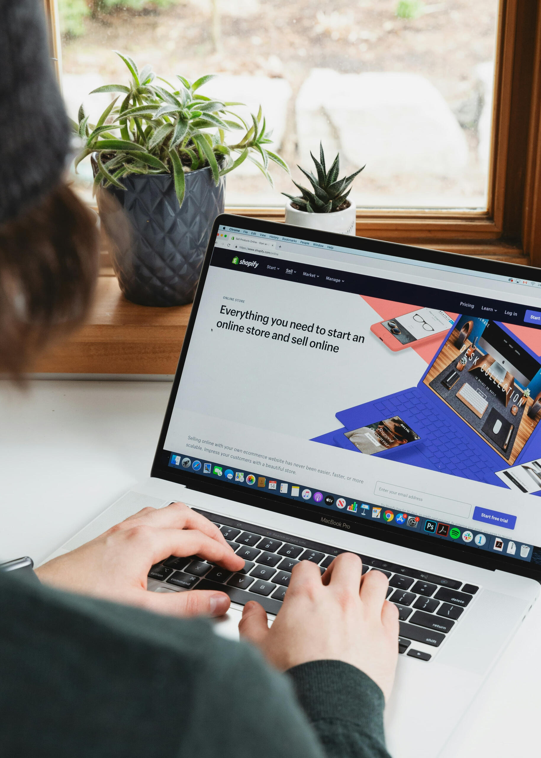 Person using laptop with Shopify homepage open, setting up an online store from home.
