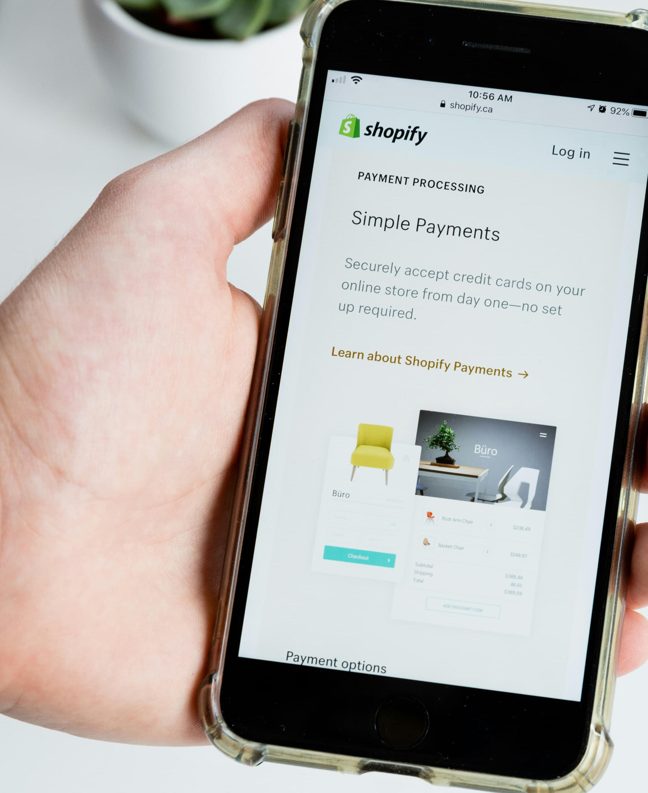 Hand holding a smartphone showing Shopify Payments setup, representing pricing and payment clarity.